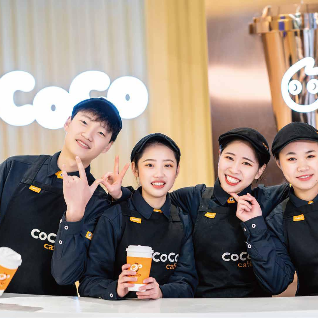 A cheerful group of CoCo employees at a CoCo boba tea franchise shop.
