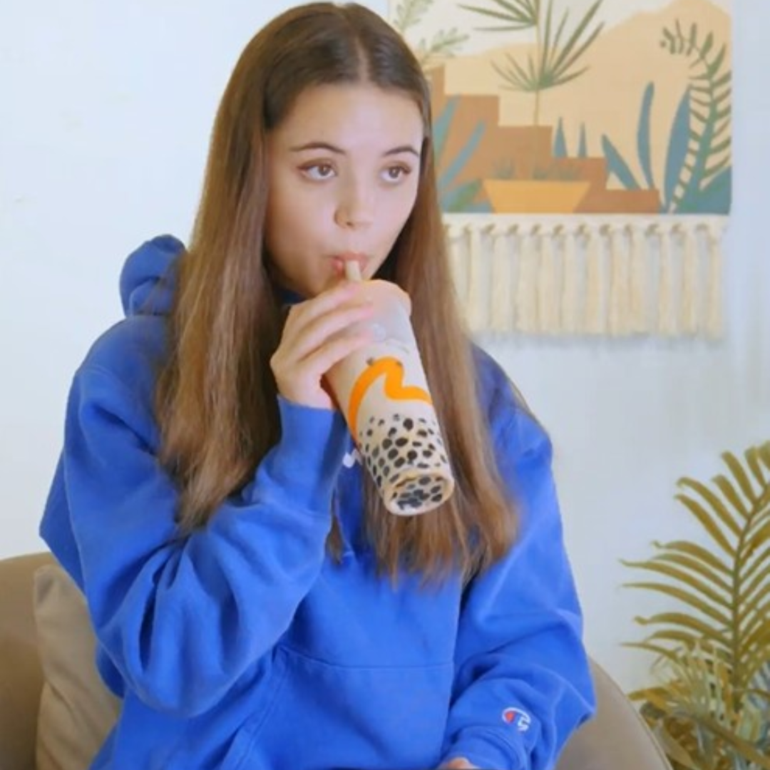 A girl in a blue hoodie drinking CoCo bubble tea.